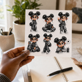 Black hand holding a monochrome kawaii planner girl sticker sheet above an open planner